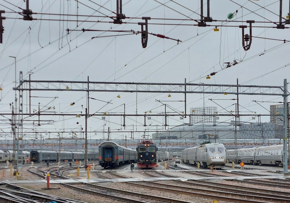 Järnvägsbangård med flera tåg, som illustrerar källor till järnvägstrafikbuller som är relevanta för mätning av omgivningsbuller, vibrationsanalys och bedömning av transportbuller.